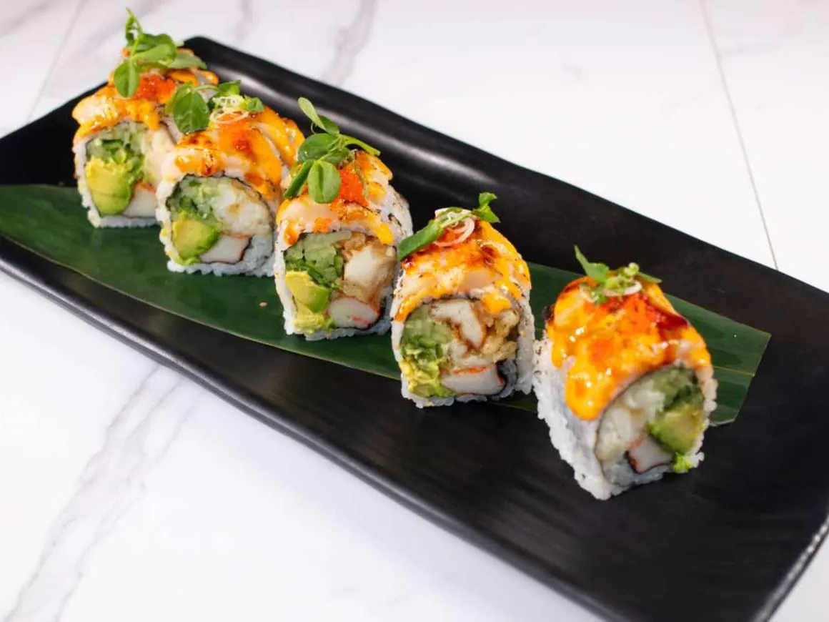 Sushi roll with crab, avocado & spicy sauce, topped with greens at Taki Sushi, a Japanese Restaurant in Toronto